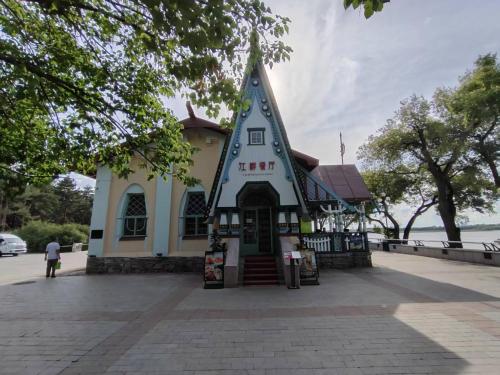a building with a pointed roof on a street at Central Street River View Apartment in Harbin