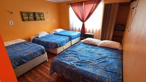 a room with three beds and a window at Hotel Casa del Profesor in Iquique