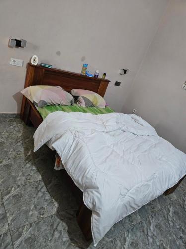 a bedroom with a large bed with white sheets at Home RÉSIDENCE OUIDAH in Ouidah