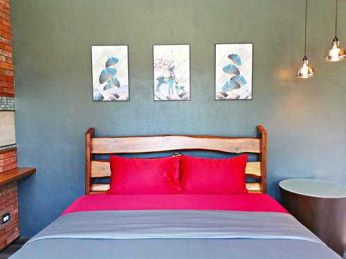 a bedroom with a red bed with four pictures on the wall at Ingsala by CafeAtLuv22 in Ban Bo Rae