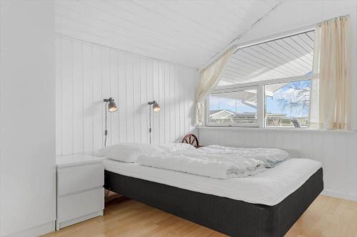 a white bedroom with a bed and a window at 8106-Ronde-Lindeparken-10 in Rønde