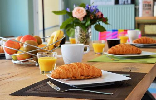 uma mesa com dois pratos de pão e sumo de laranja em B&B Louis-Favre 21 em Neuchâtel