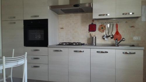 a kitchen with white cabinets and a stove at Casa Vacanze Le Due Palme in Miglianico