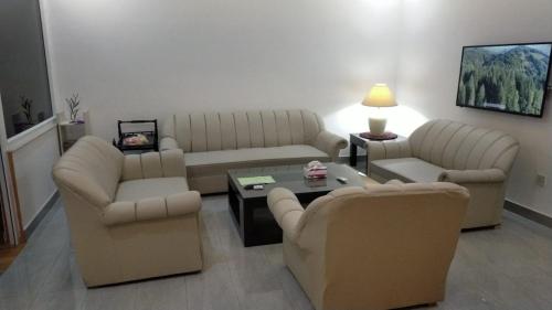 a living room with couches and a coffee table at Airport Layover Family Lodge in Islamabad