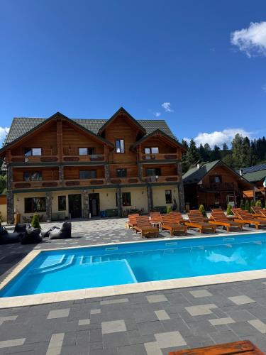 a lodge with a swimming pool in front of a building at Готель TWINS РАЙ in Vorokhta