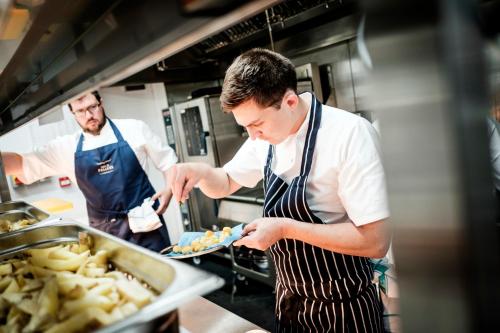 two men in a kitchen preparing food in a kitchen at The Queen's Head in Kingston upon Thames