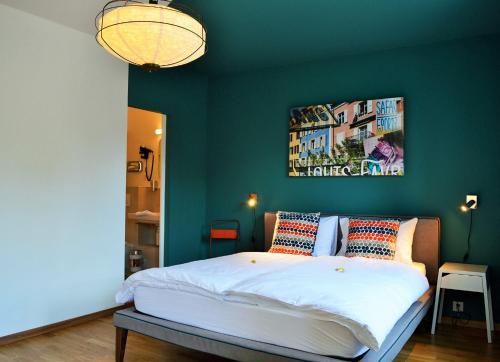 1 dormitorio con 1 cama con pared verde en B&B Louis-Favre 21, en Neuchâtel