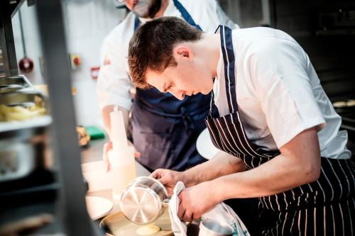 a man wearing an apron preparing food in a kitchen at The Queen's Head in Kingston upon Thames