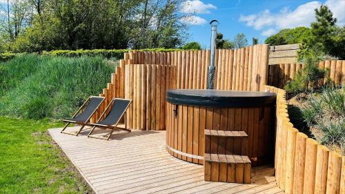 a wooden deck with two chairs and a hot tub at 8113-Ronde-Strandvejen-91 in Rønde