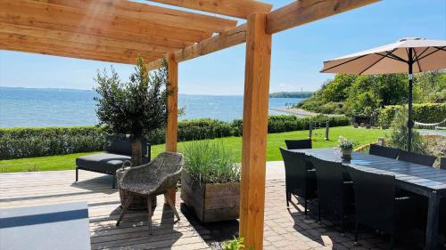a patio with a table and chairs and an umbrella at 8113-Ronde-Strandvejen-91 in Rønde