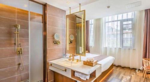 a bathroom with a sink and a shower with a mirror at James Joyce Coffetel Luoyang Longmen High-speed Railway Station Baolong Plaza in Luoyang