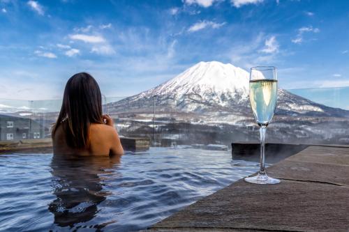 a woman sitting in a swimming pool next to a wine glass at The Vale Niseko in Kutchan
