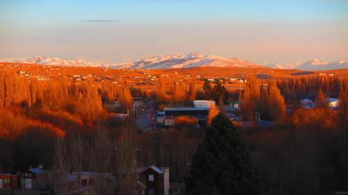 a snowy mountain range with a view of a city at America Del Sur Calafate Hostel in El Calafate
