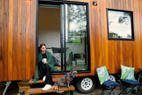a woman sitting on the window of a house with a dog at Kookaburra's Perch in Millgrove