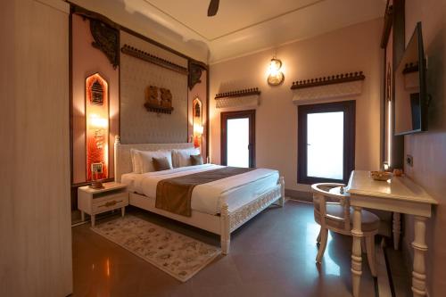 a bedroom with a bed and a desk and a desk at BrijRama Palace, Varanasi - By the Ganges in Varanasi