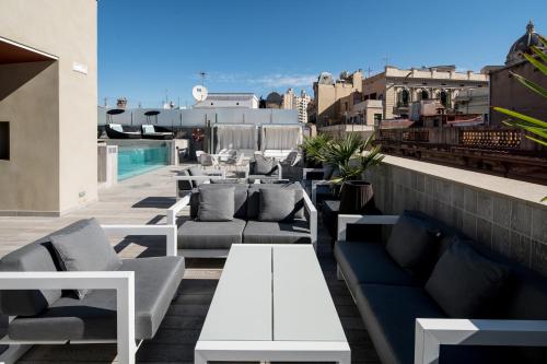 a patio with couches and tables on a roof at Catalonia Magdalenes in Barcelona
