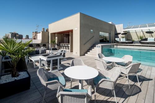 eine Terrasse mit Tischen und Stühlen neben einem Pool in der Unterkunft Catalonia Magdalenes in Barcelona