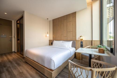 a bedroom with a bed and a table and a window at SHAN Villas Sukhumvit in Bangkok
