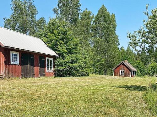 an old red barn and a house in a field at 5 person holiday home in HÄRADSBÄCK-By Traum in Ryd