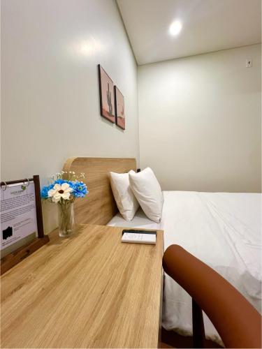 a room with a bed and a table with flowers at Vuon Xanh Hotel & Cafe in Xóm Mỹ Xuân