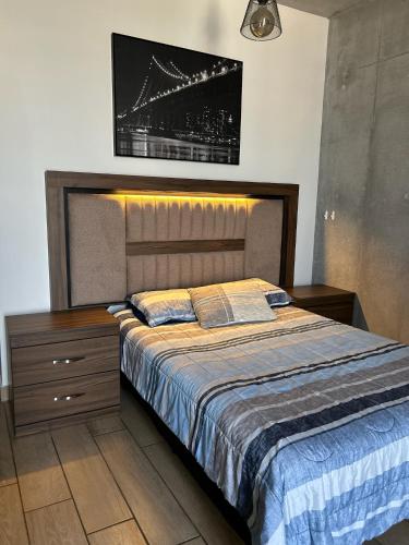 a bedroom with a large bed with a nightstand and avertisement at Depa en el corazón de Monterrey in Monterrey