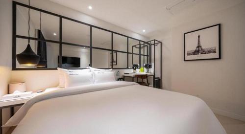 a bedroom with a large white bed and a desk at Wonju Bellino Hotel in Wonju