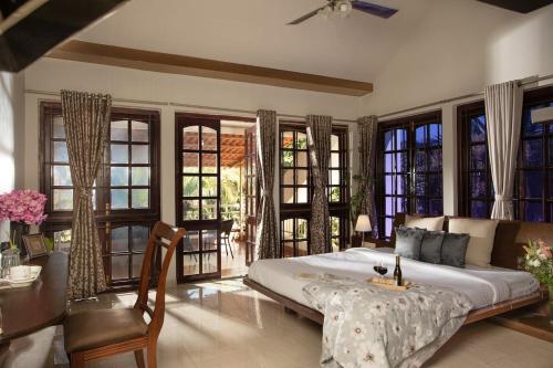 a bedroom with a bed and a table and windows at Nirvana Luxurious Pool Garden Villa in Vasai in Vasai