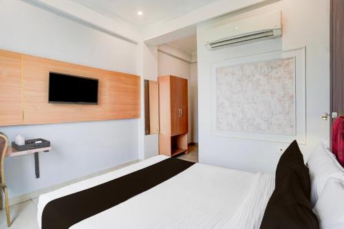 a bedroom with a bed and a tv on the wall at Super Townhouse Oak Arvindo Park Indira Nagar Formerly Rama Inn in Vibhuti Khand