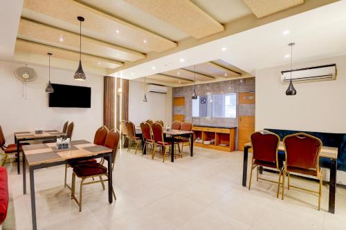 a dining room with tables and chairs and a tv at Super Townhouse Oak Arvindo Park Indira Nagar Formerly Rama Inn in Vibhuti Khand