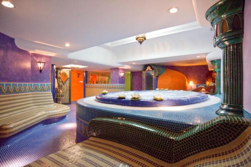 um quarto com uma cama grande e um banco em Amira Boutique Hotel Hévíz Wellness & Spa em Hévíz