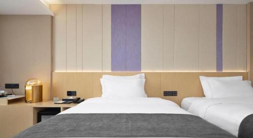 a hotel room with two beds and a desk at Lavande Hotel Guangzhou Quzhuang Metro Station in Guangzhou