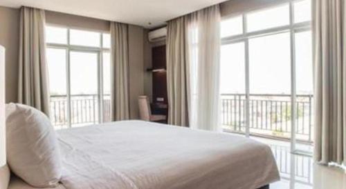 a bedroom with a bed and a balcony with windows at Karlita Hotel Tegal in Tegal