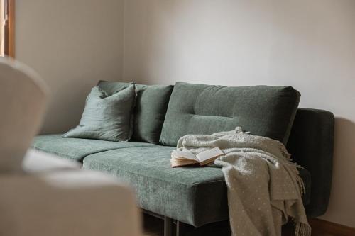 a green couch with a book on top of it at The Willows Coastal Retreat in Old Ocean Grove in Ocean Grove