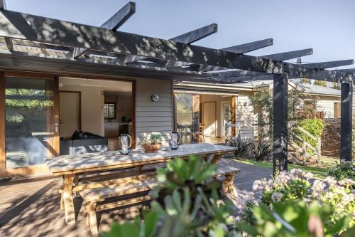 a patio with a wooden table and a pergola at The Willows Coastal Retreat in Old Ocean Grove in Ocean Grove