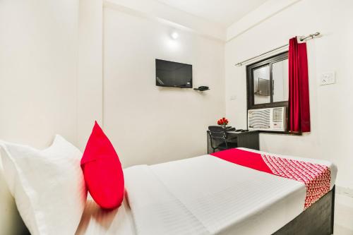 a bedroom with a white bed with red pillows at Hotel O Q7 in Kota