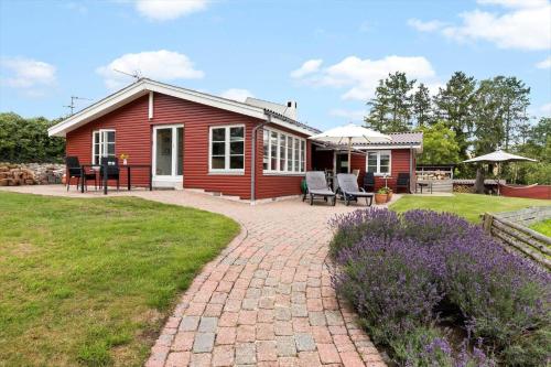 a small red house with a patio and lawn at 8117-Ronde-Strandvejen-93 in Rønde