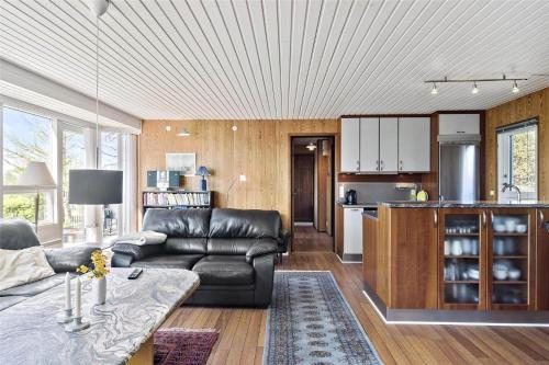 a living room with a leather couch and a kitchen at 8442-Ronde-Lindeparken-56 in Rønde