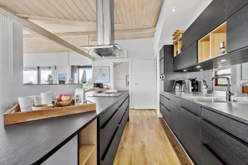 a kitchen with black cabinets and a wooden counter top at 84164-Ronde-Stenhojvej-17 in Rønde