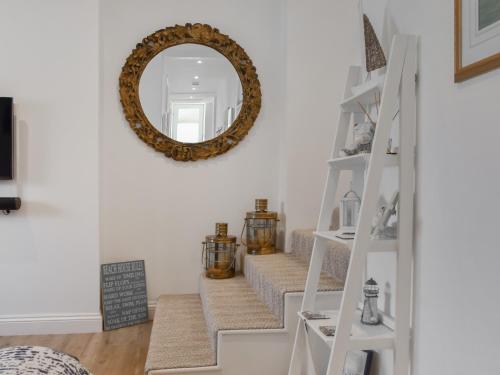 Un espejo en la pared encima de las escaleras en una sala de estar. en Magdala Garden, en Salcombe