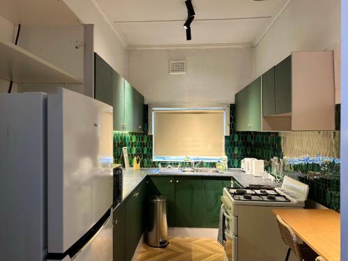 una cucina con mobili verdi e un frigorifero bianco di Modern Vintage King and Single Rooms a Bankstown