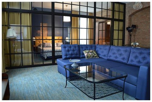 uma sala de estar com um sofá azul e uma mesa de vidro em Apartamenty Róże i Zen em Toruń