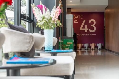 a lobby with two chairs and a vase of flowers at Gate43 Airport Hotel in Lat Krabang