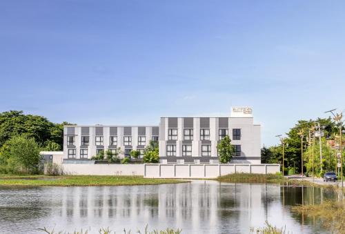 a building in front of a body of water at Gate43 Airport Hotel in Lat Krabang