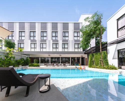a hotel with a swimming pool in front of a building at Gate43 Airport Hotel in Lat Krabang