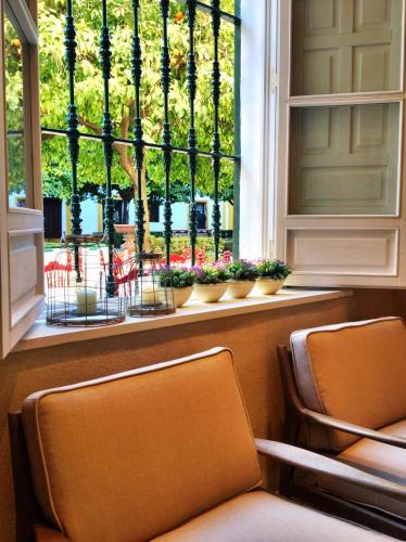 two chairs in front of a window with flowers at Hotel Boutique Elvira Plaza in Seville