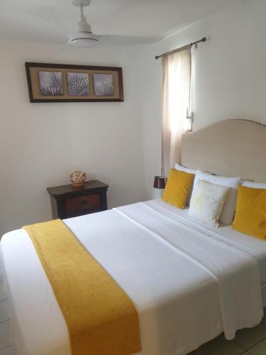 a bedroom with a large bed with yellow and white pillows at Chermakish Exceptional View Logement 3 Chambres, Piscine in Marigot