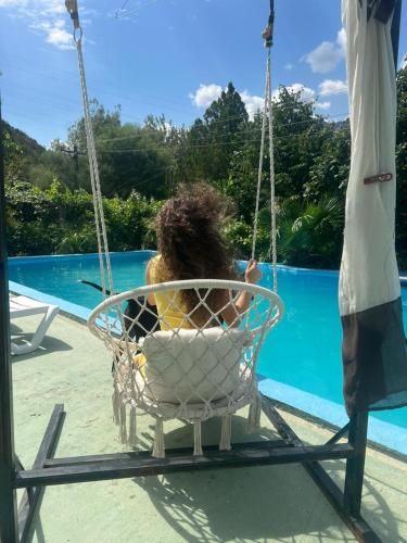 a woman sitting in a swing by a pool at Domus Komanesse - Guest Houses in Koman