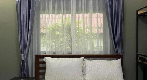 a bedroom with a window with blue and white curtains at Ma-Kham Forest Resort in Nakhon Nayok