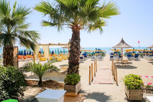 a beach with chairs and palm trees and the ocean at Hotel Bella Vista in Durrës
