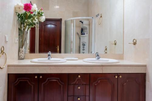 Un baño con dos lavabos y un jarrón de flores. en Villa Candelaria Sevilla Aljarafe, en Bormujos
